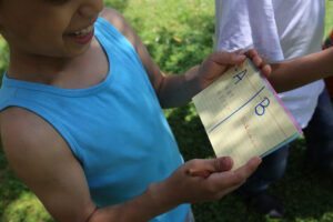 teaching refugee communities in Lebanon: a little boy reading a book outside