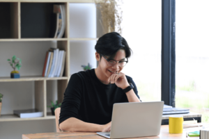 Asian guy smiling with a computer
